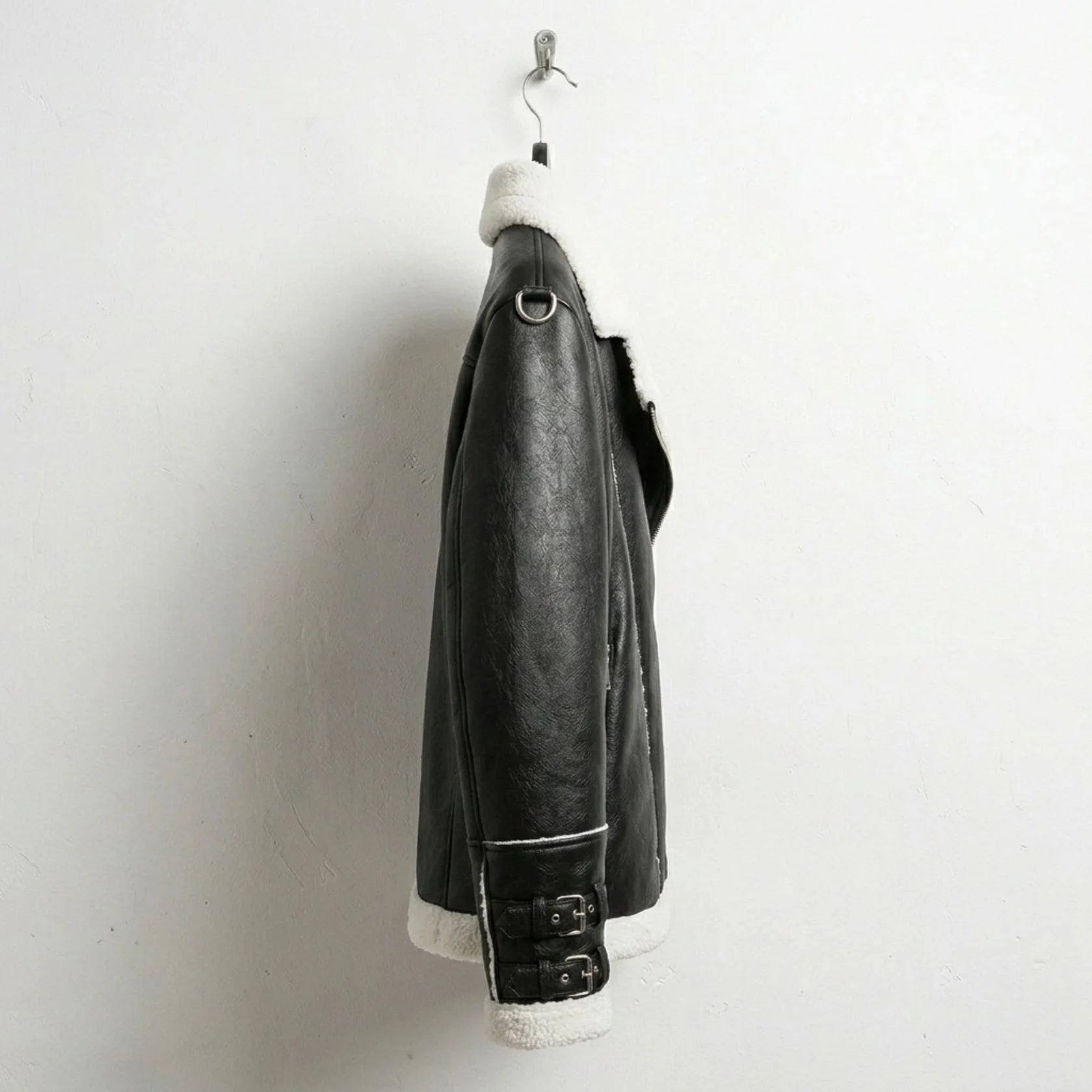 side view mens black faux leather biker jacket with sherpa trim and buckled cuffs.