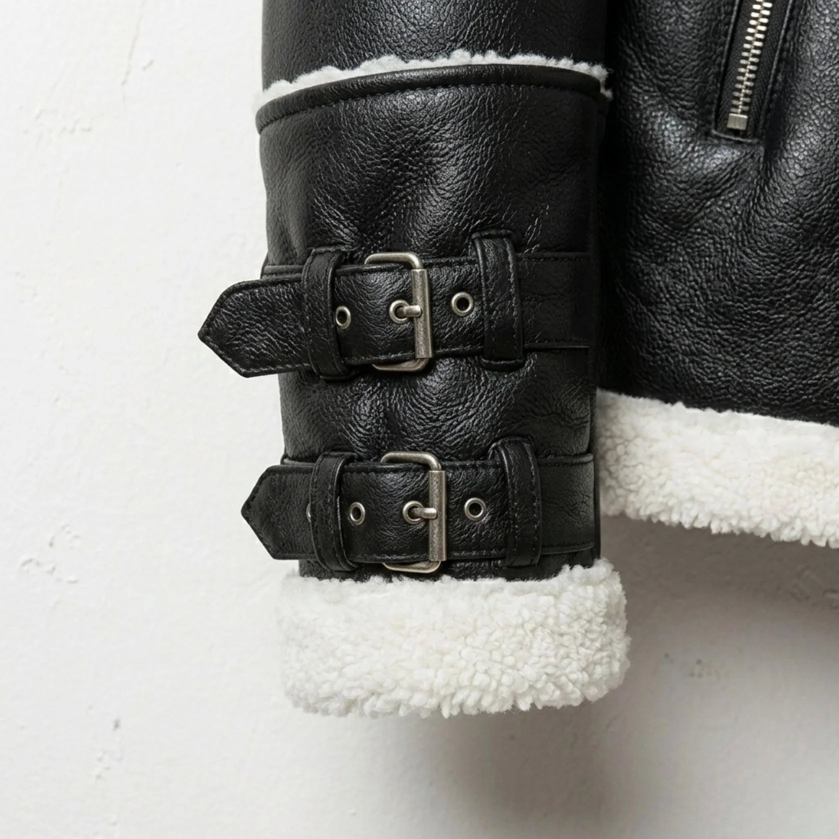 close up double buckle belted cuffs and sherpa trim on mens faux shearling jacket.
