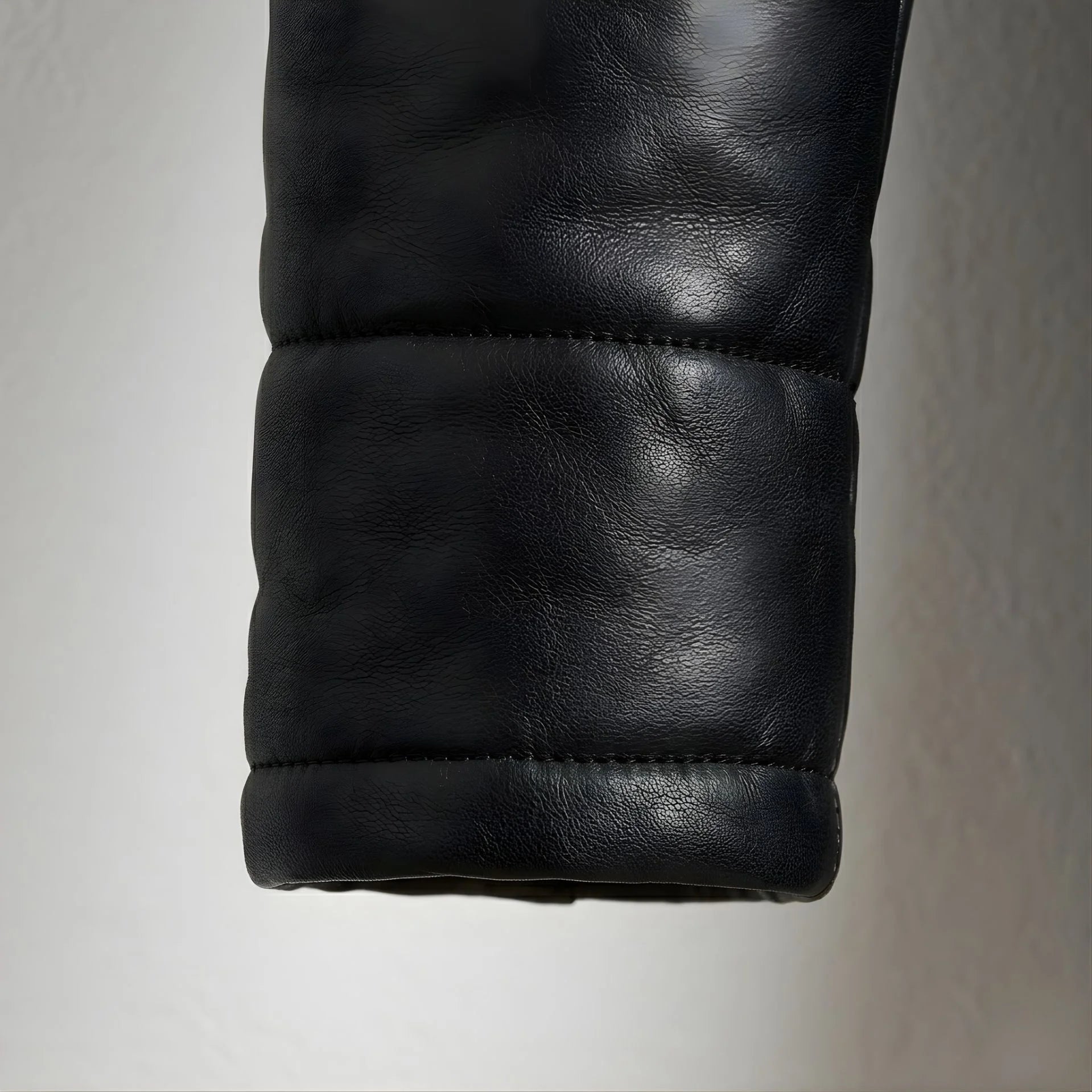 Detail of padded cuff on men's black genuine leather puffer coat.