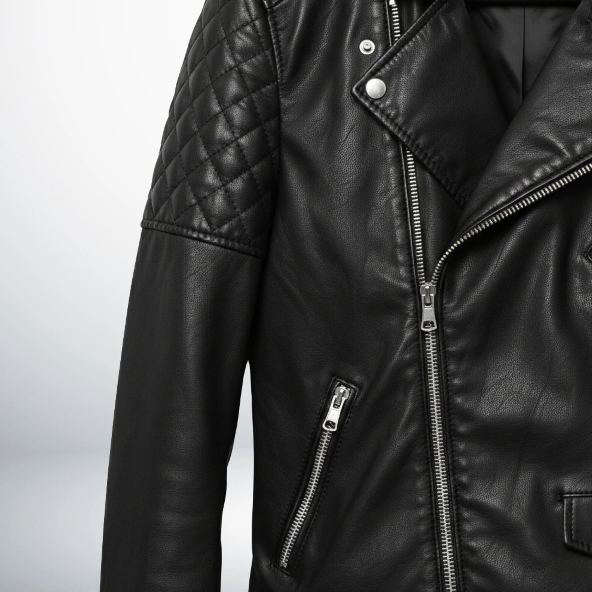 detail of quilted shoulder and zipper pocket on men's black leather motorcycle jacket.