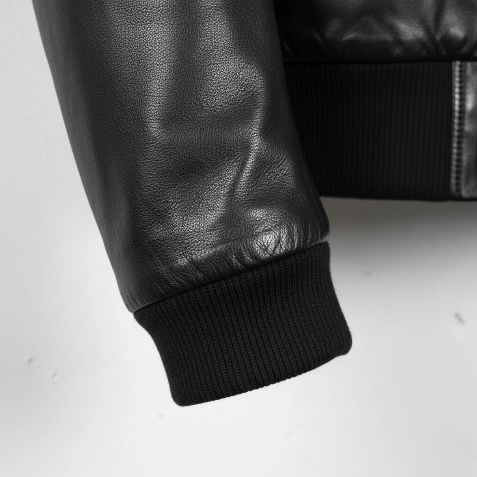 close up of rib knit cuff on men's black leather bomber jacket.