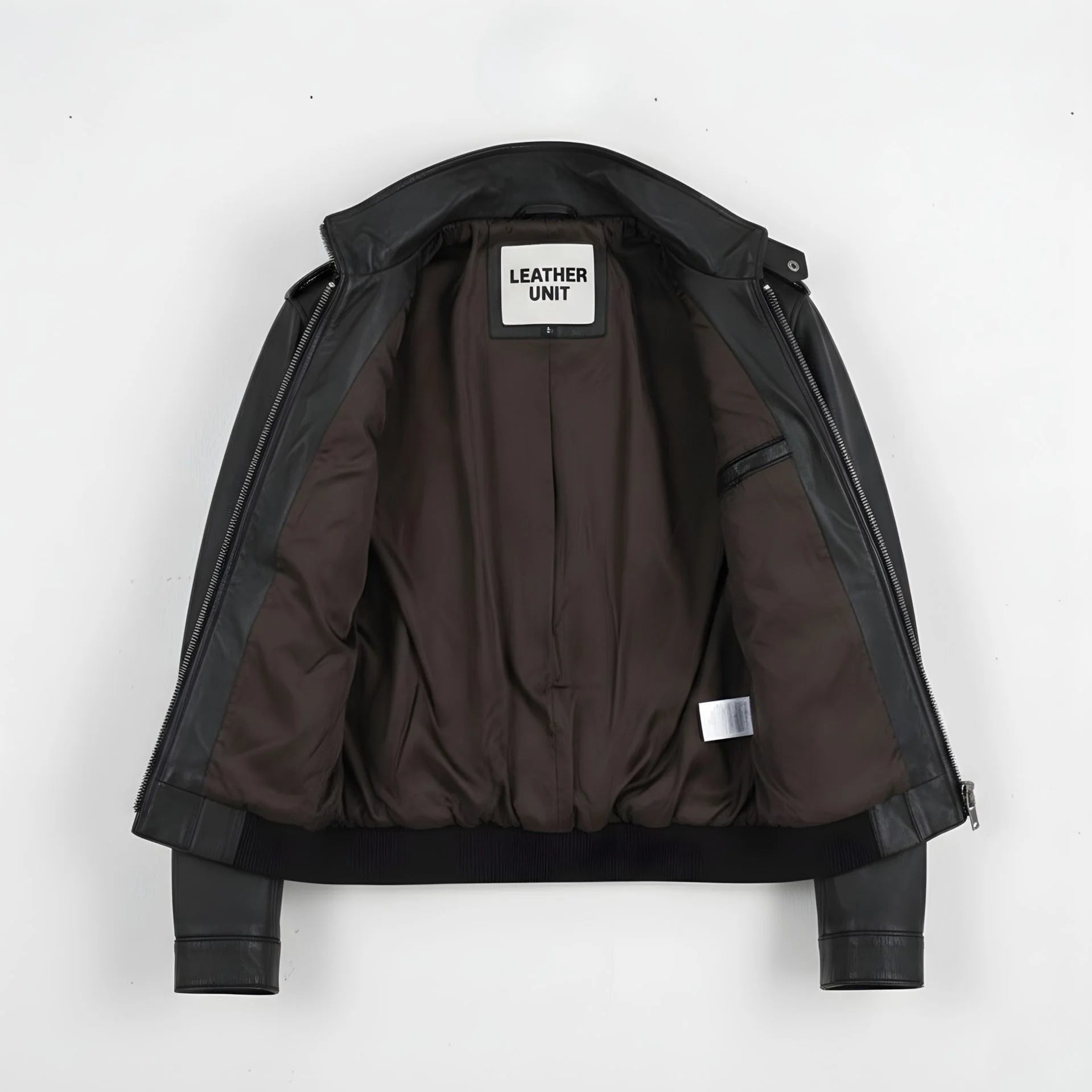 inside of men's black leather field jacket showing brown lining and inner pocket.