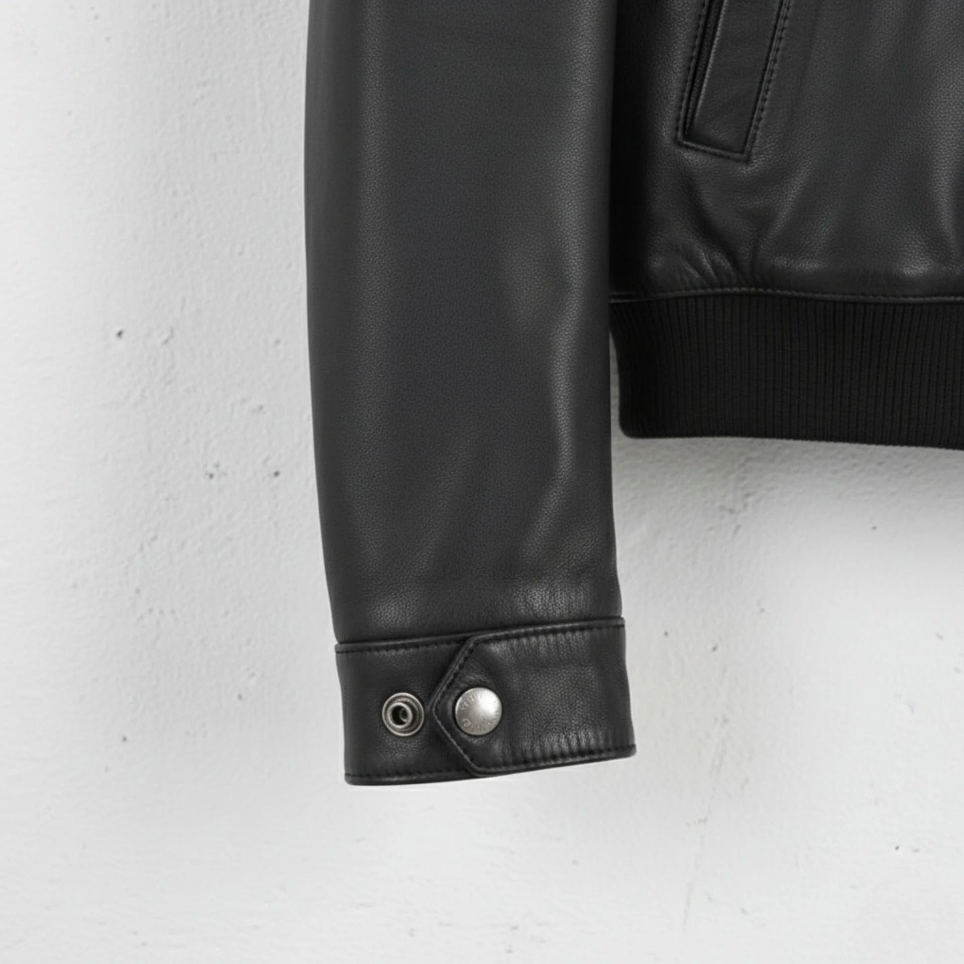 cuff and snap detail on sleeve of men's black leather field bomber jacket.
