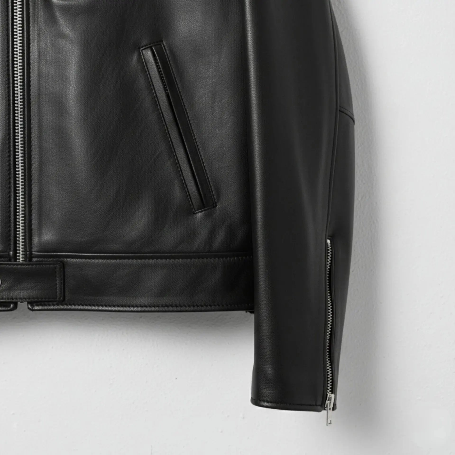 lower front pocket and hem detail on men's slim fit black leather jacket.