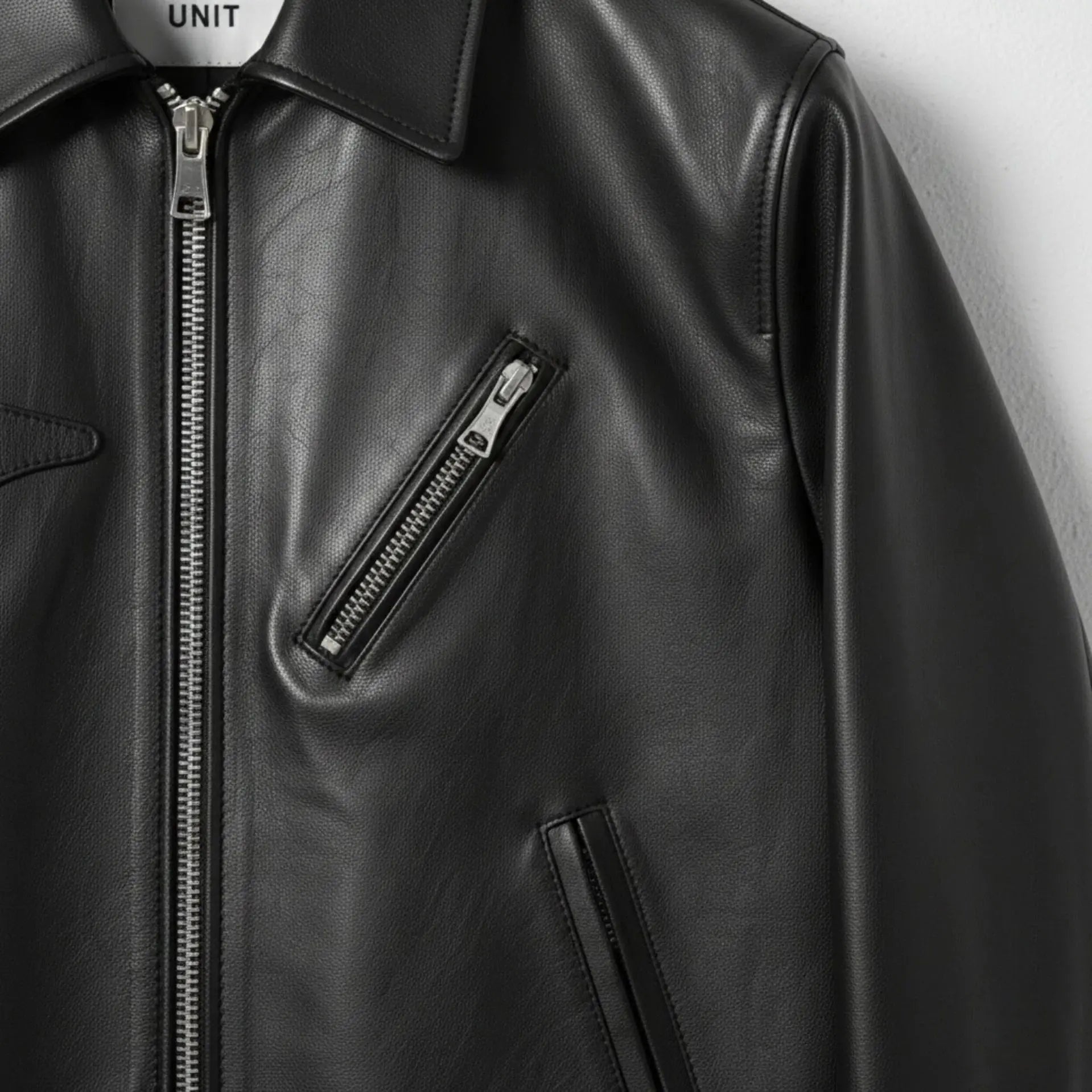 detail of angled chest zip pocket on men's black leather biker jacket.