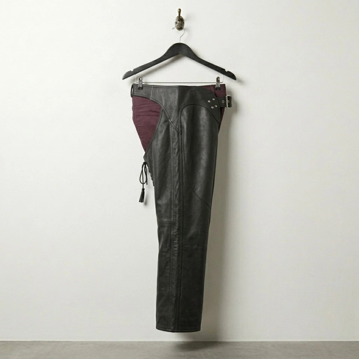 Side profile of men's black leather chaps showing full-length leg coverage