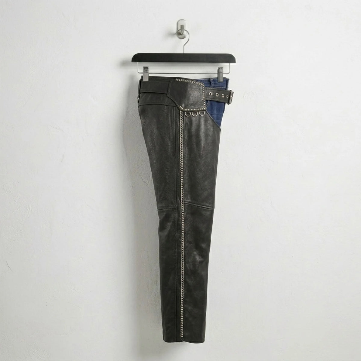 Side profile of men's black leather chaps with full-length zipper and studs.