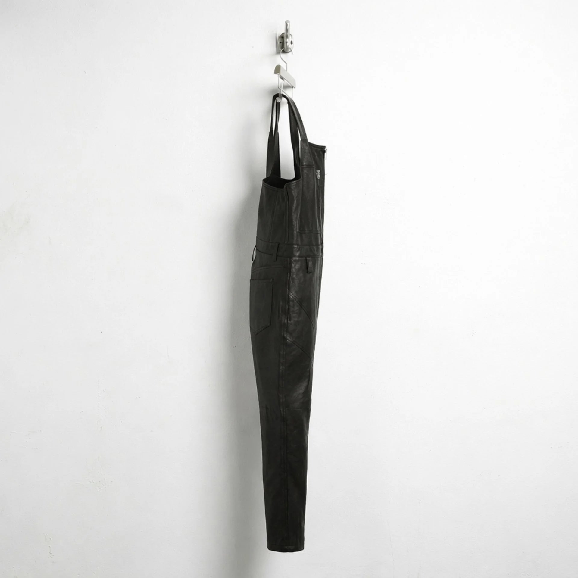 Side profile of men's black leather overalls with slim straight leg