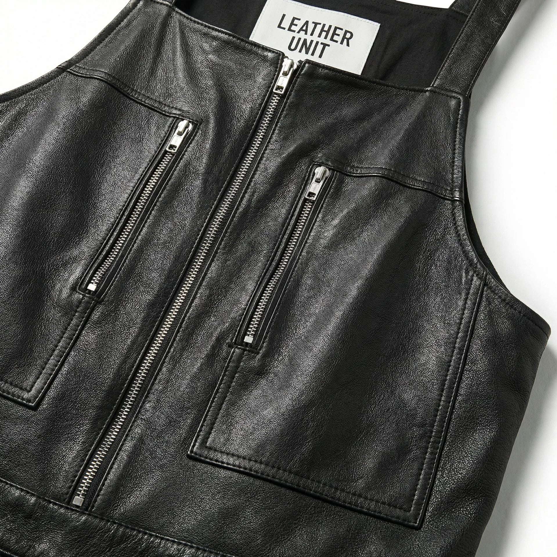 Close-up of bib and twin zip chest pockets on men's black leather overalls