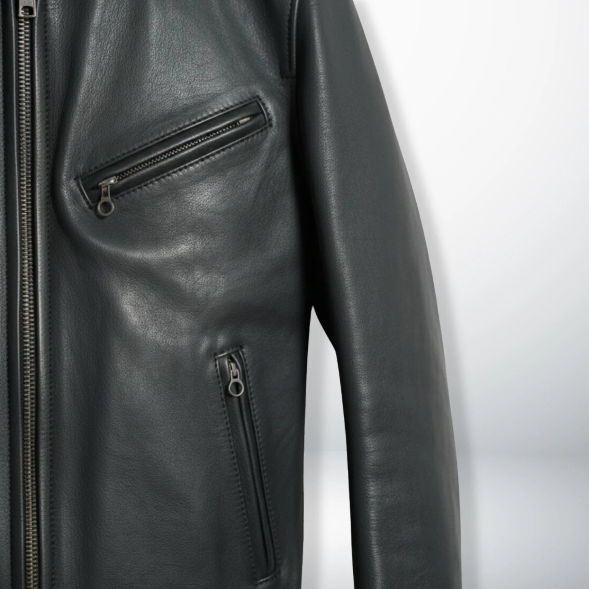 detail of chest and hand zipper pockets on men's black leather rider jacket.