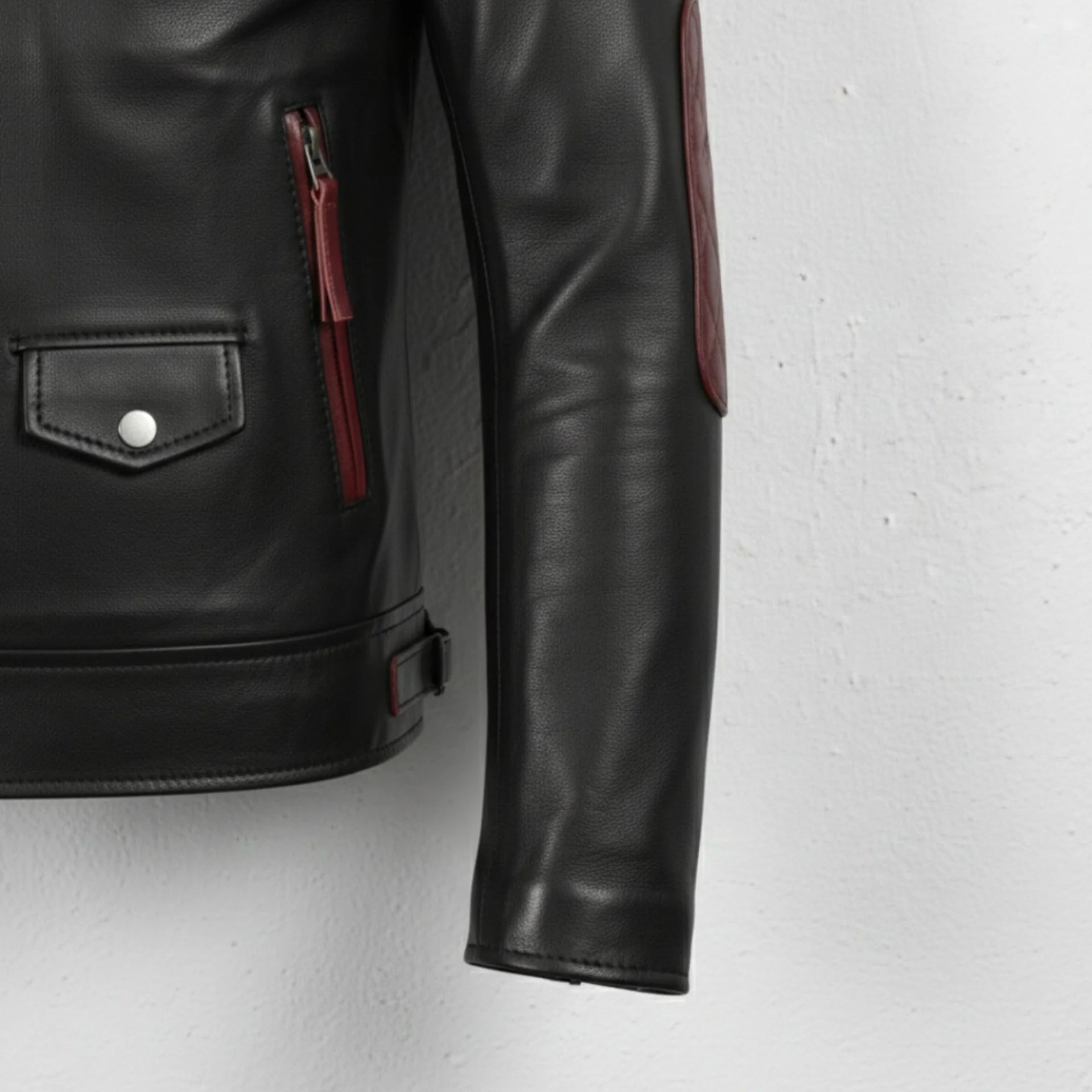 hem and side adjuster tabs on men's black and maroon quilted biker leather jacket.