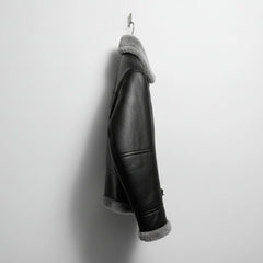 side profile mens black shearling bomber leather jacket hanging on wall.
