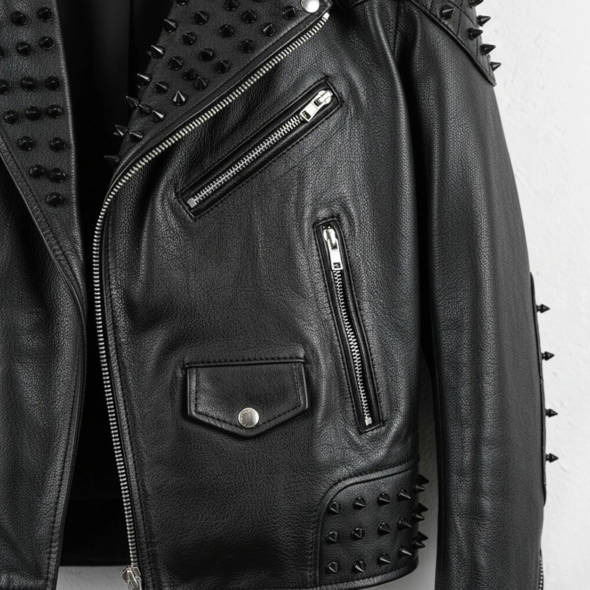 detail of chest zip pockets and coin pocket on men's black studded biker jacket.