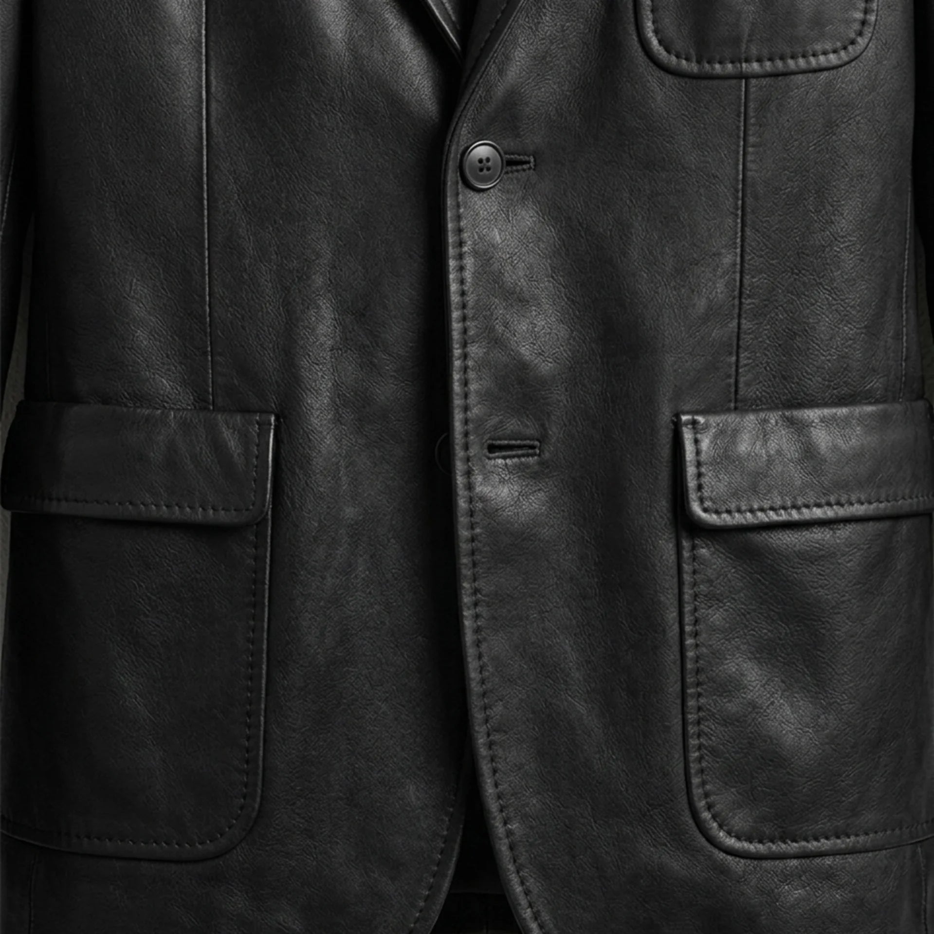 Patch pockets and button close up on men’s black leather blazer