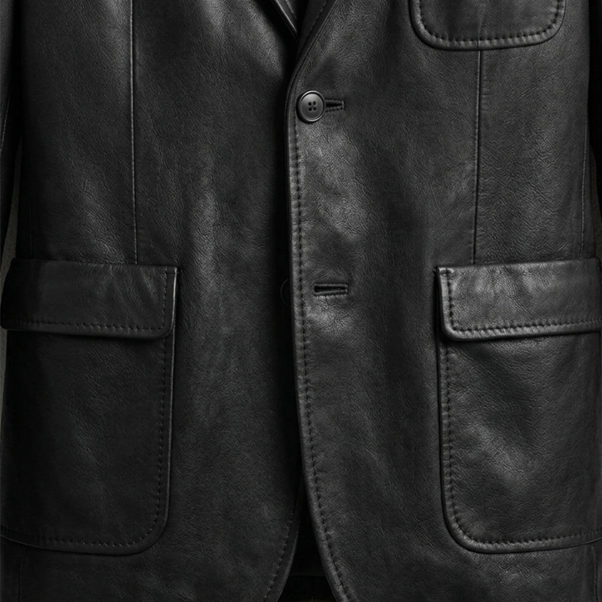 Patch pockets and button close up on men’s black leather blazer