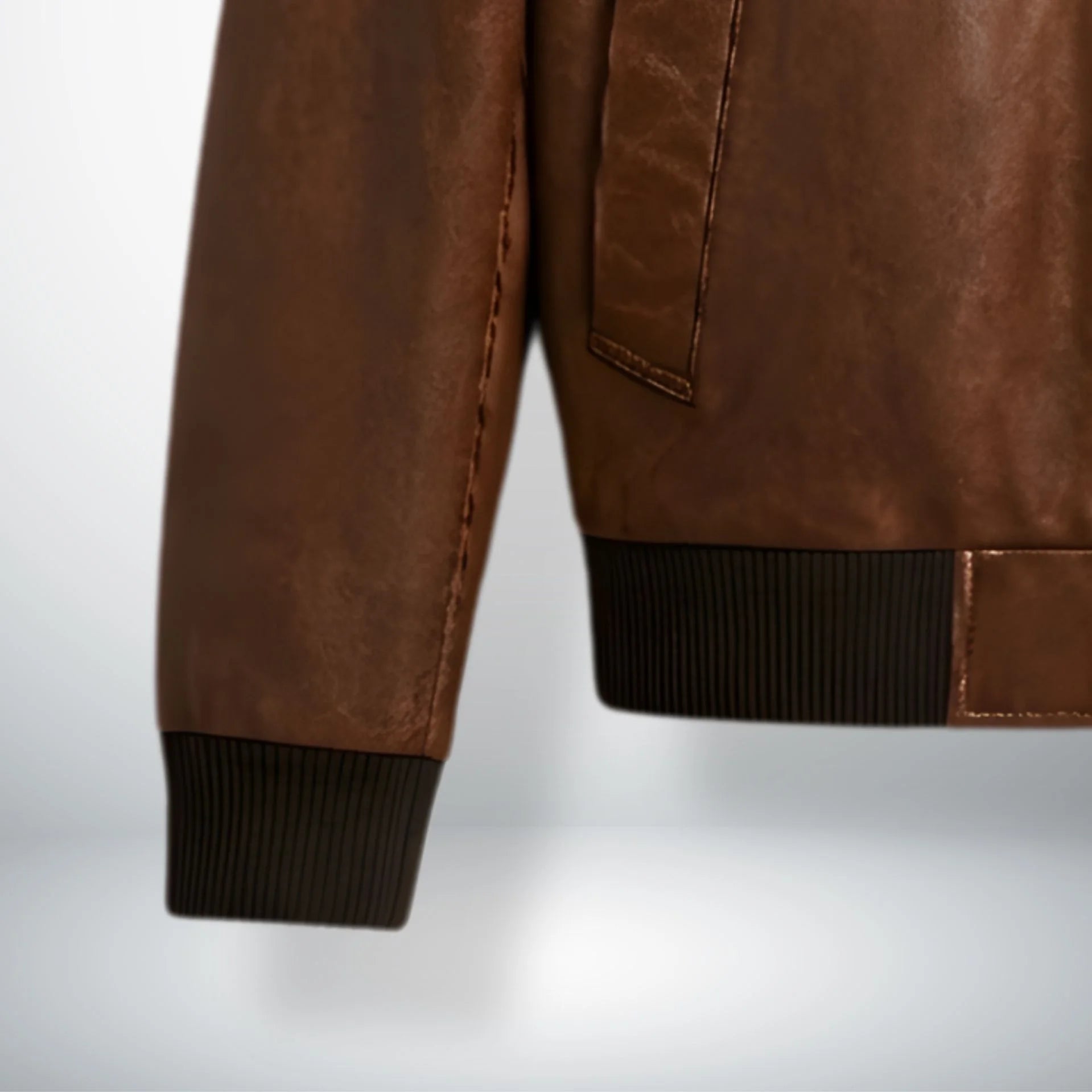 close up of ribbed cuffs and hem on brown bomber leather jacket.