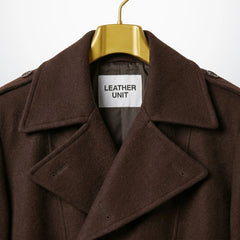 Close up of notch lapel collar and Leather Unit label on brown overcoat.