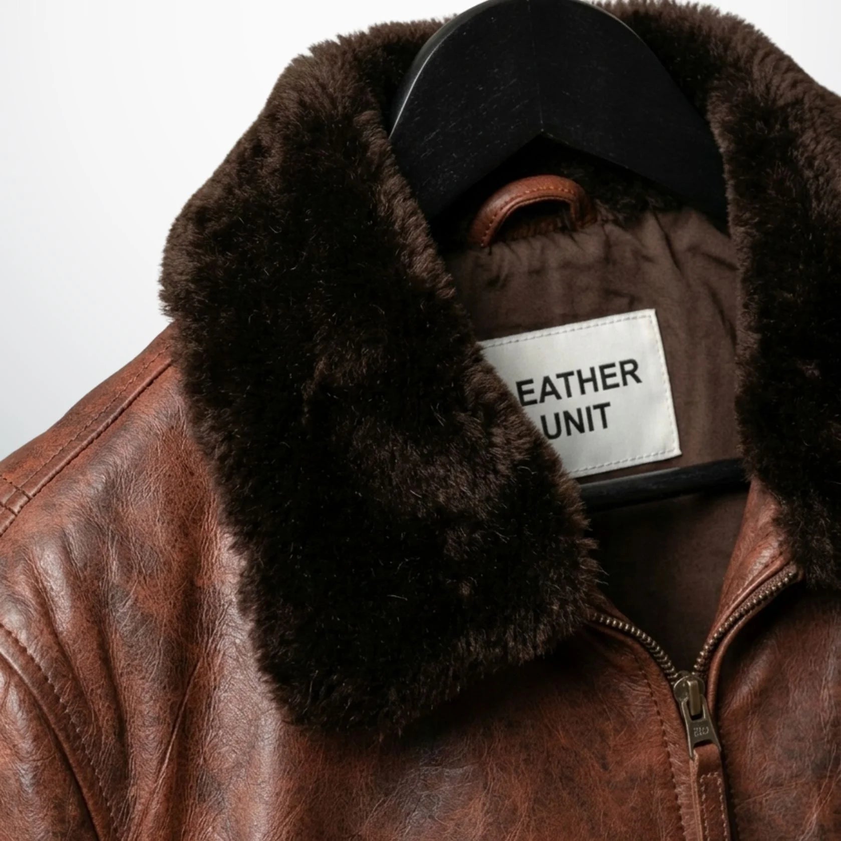 close up dark brown faux fur collar and label on mens brown leather jacket.