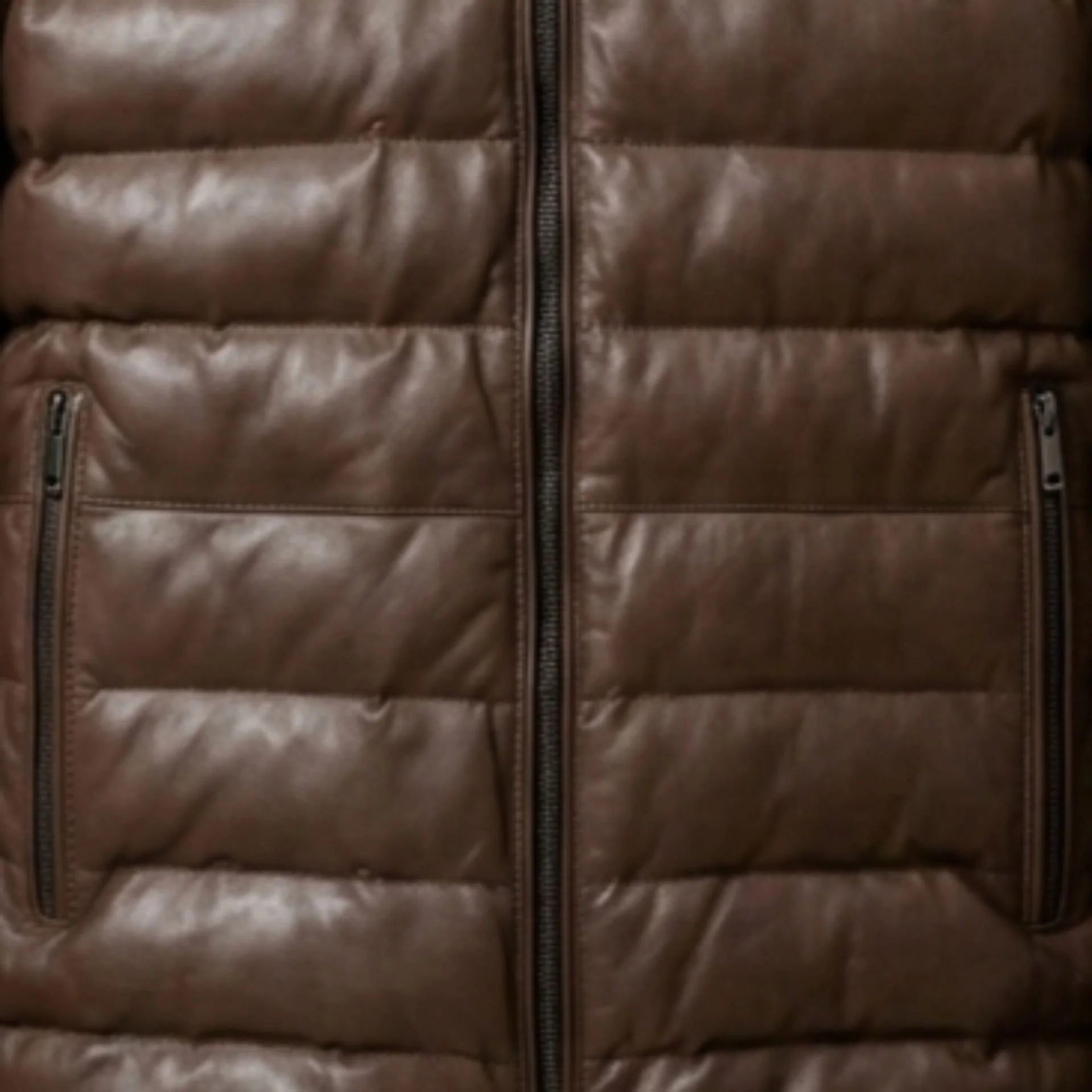 Close-up of vertical zip pockets and heavy-duty zipper on brown leather puffer jacket