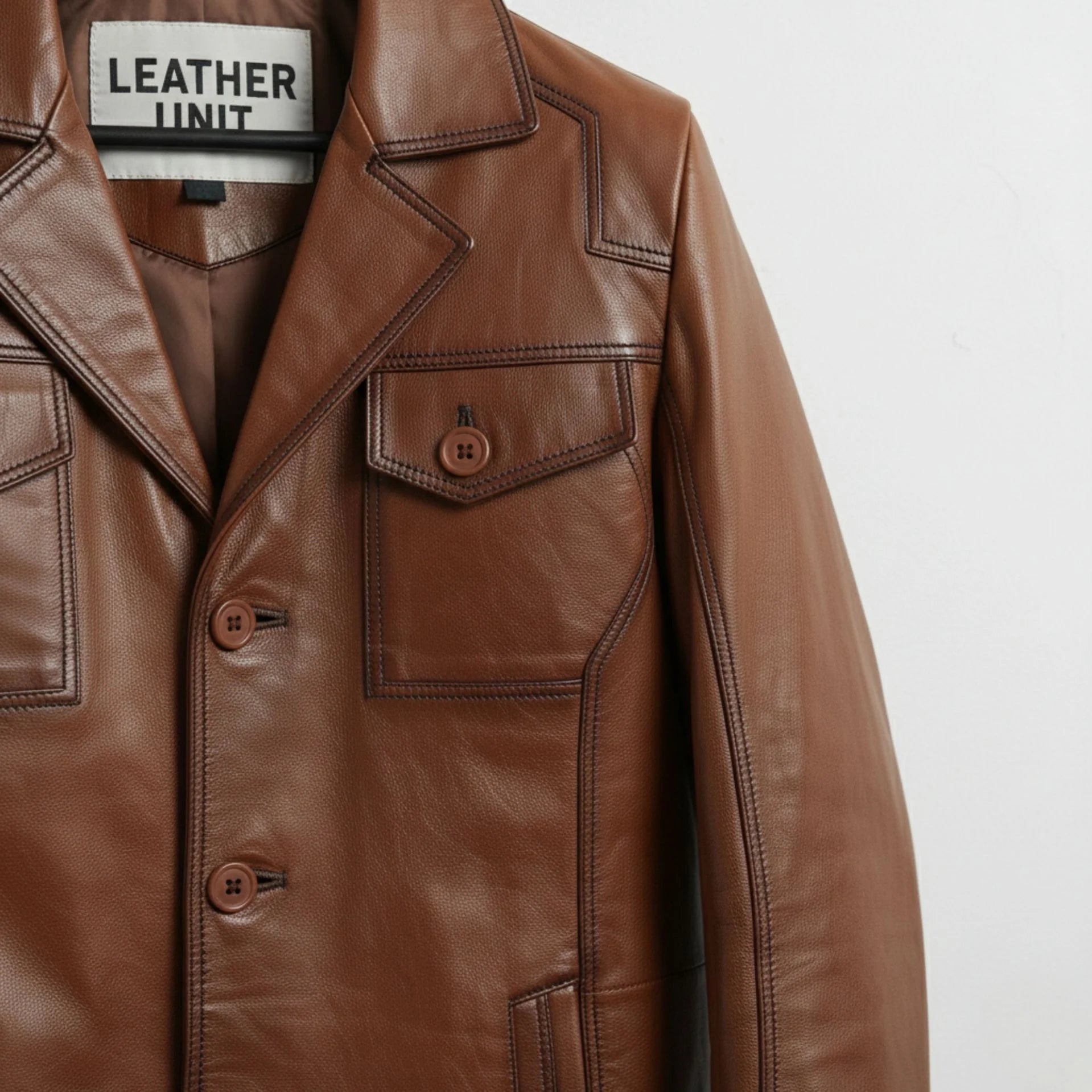 detail of stitching and chest pocket on men's brown leather jacket.