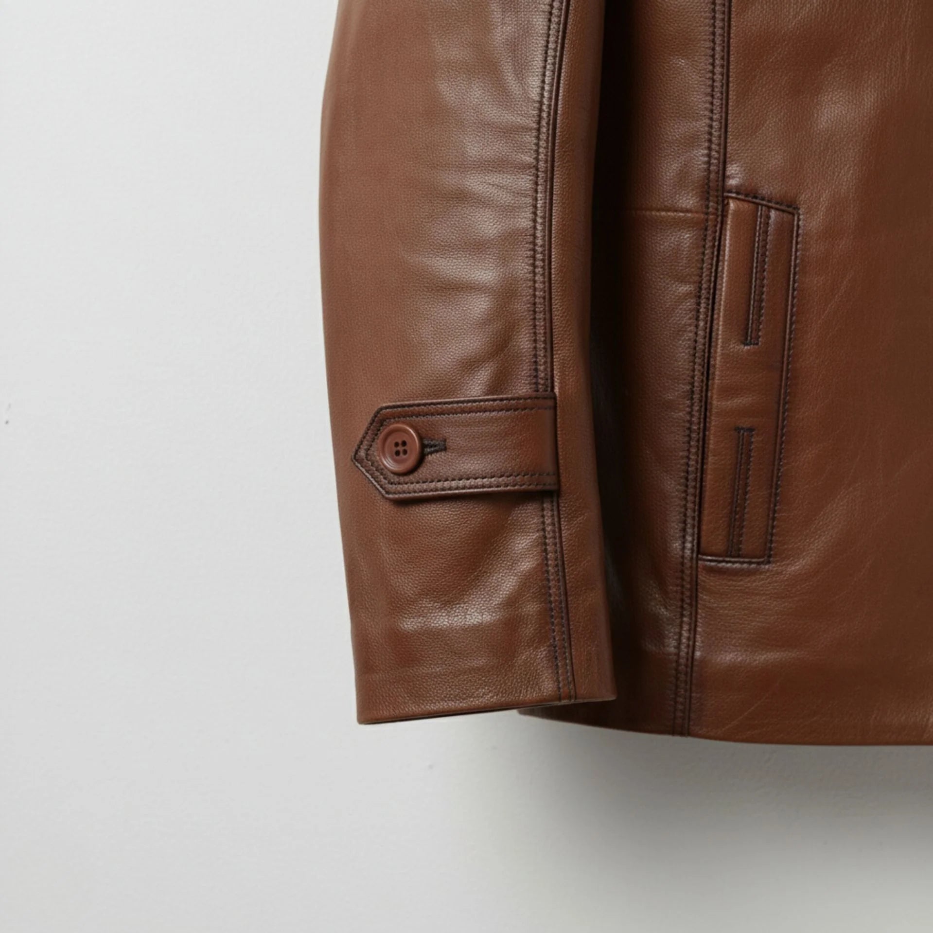 cuff and pocket close up on men's brown leather blazer coat.