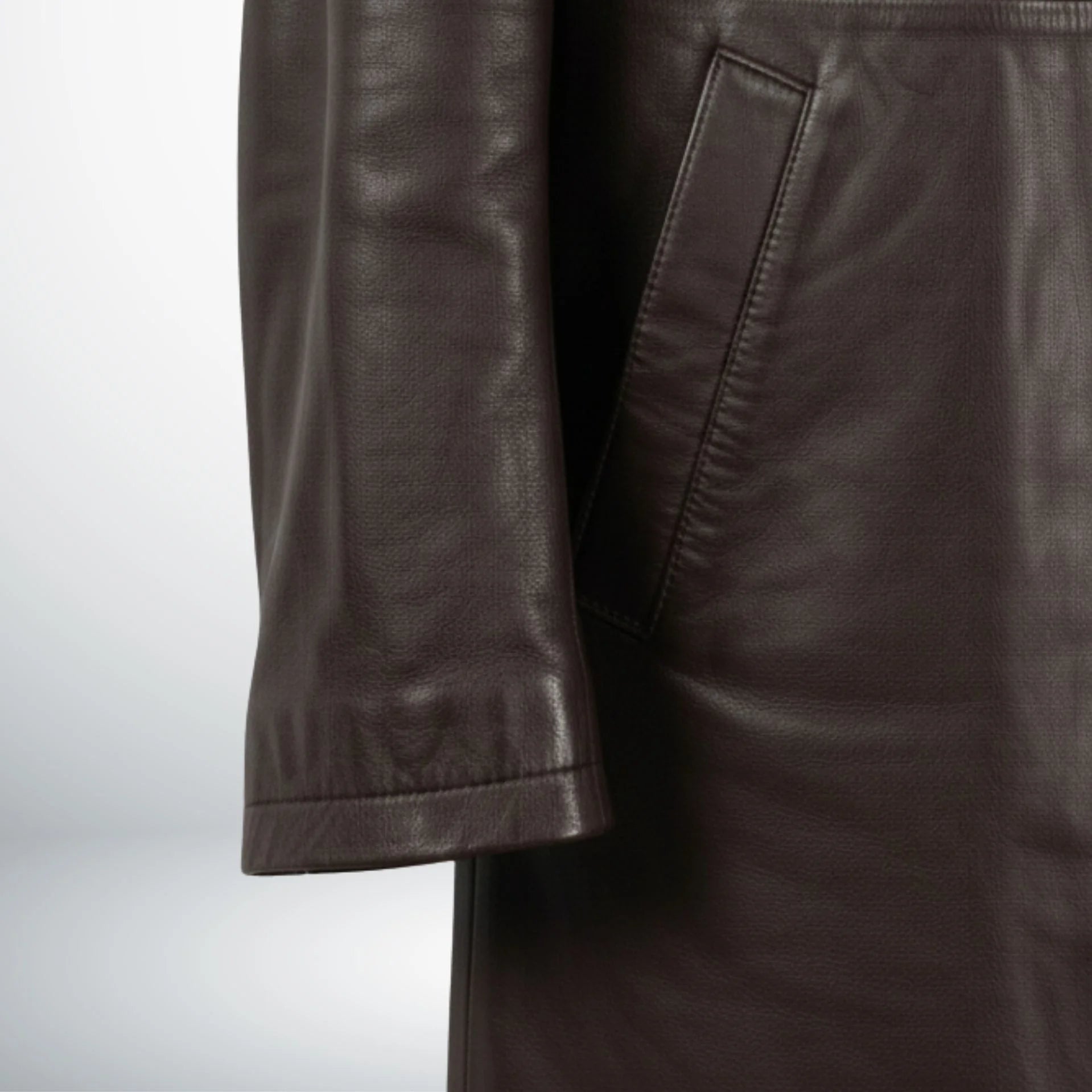 Detail of sleeve and welt pocket on men's dark brown leather coat.