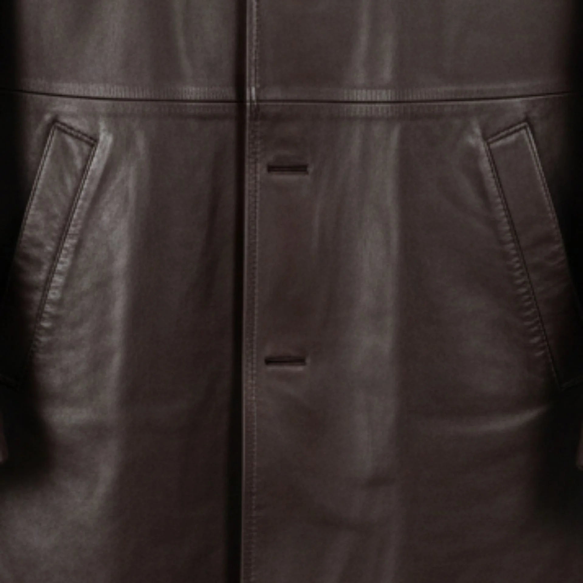 Close up of front welt pockets and button placket on men's brown leather car coat.