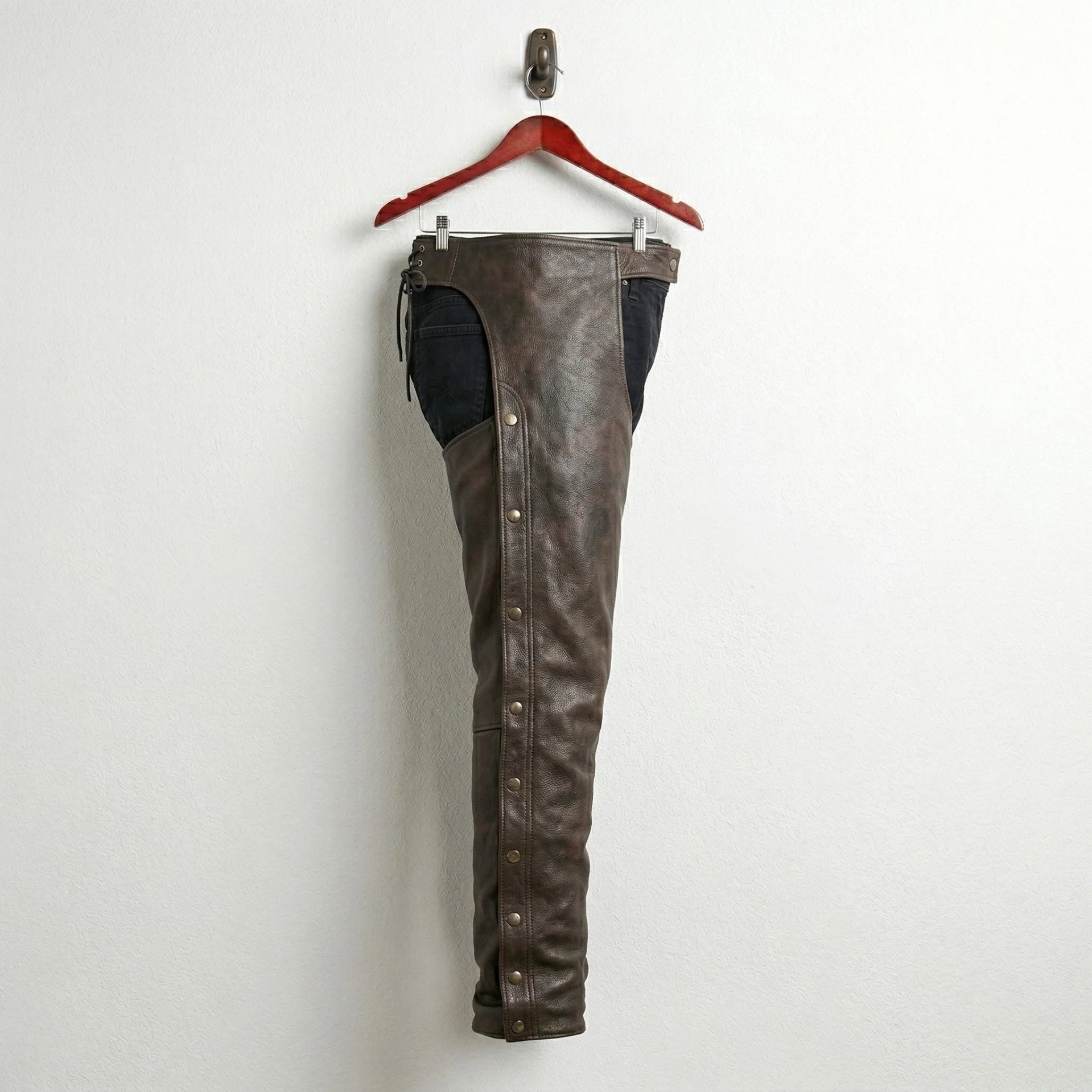 Side profile of men's brown leather chaps with snap leg closures