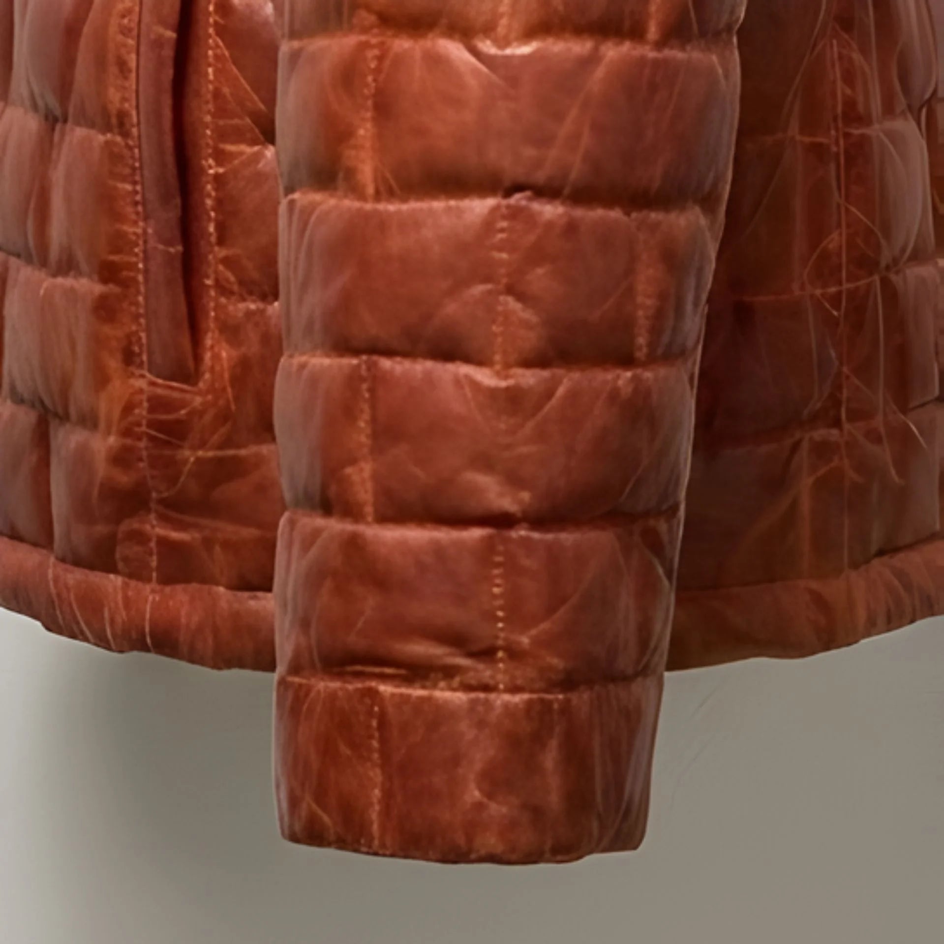 Detail of cuff and quilting on men's brown leather light down jacket.