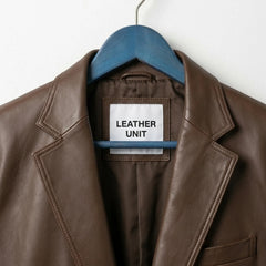 Close up of notch lapel and Leather Unit label on brown leather blazer