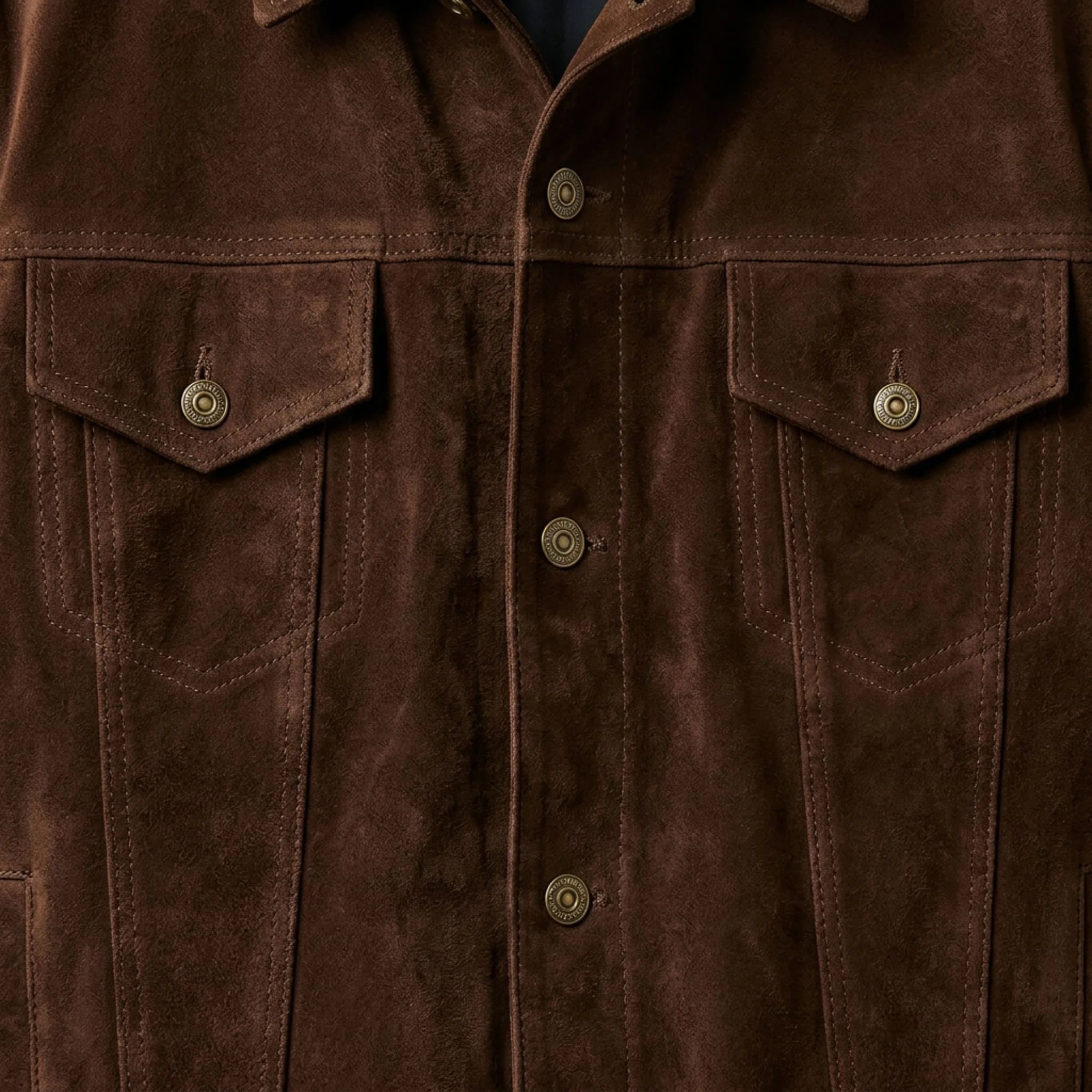 Close up of front buttons and chest pockets on men's brown suede trucker jacket.