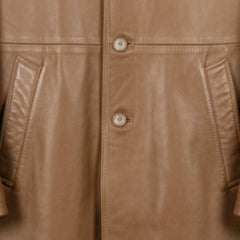 Close up of front buttons and angled welt pockets on men's camel leather coat.