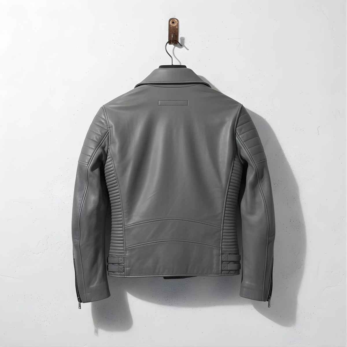 back view of men's grey leather moto jacket with ribbed side panels.