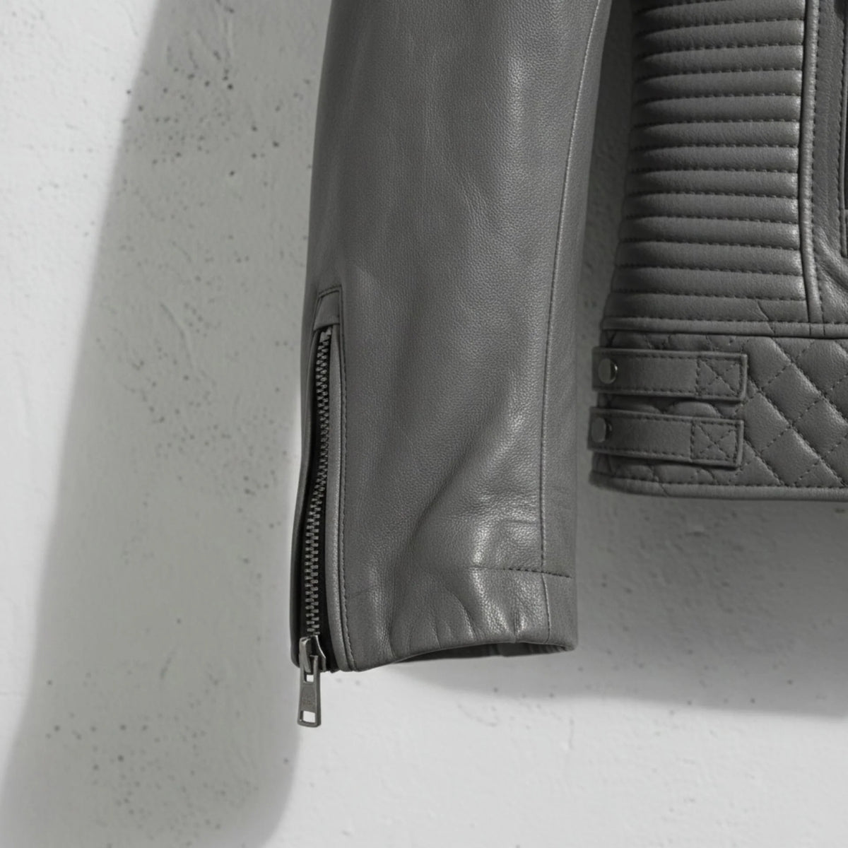 sleeve and cuff zipper close up on men's grey leather motorcycle jacket.