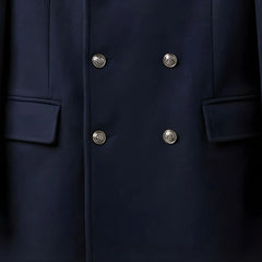 Close up of silver double breasted buttons and flap pockets on men's navy coat.