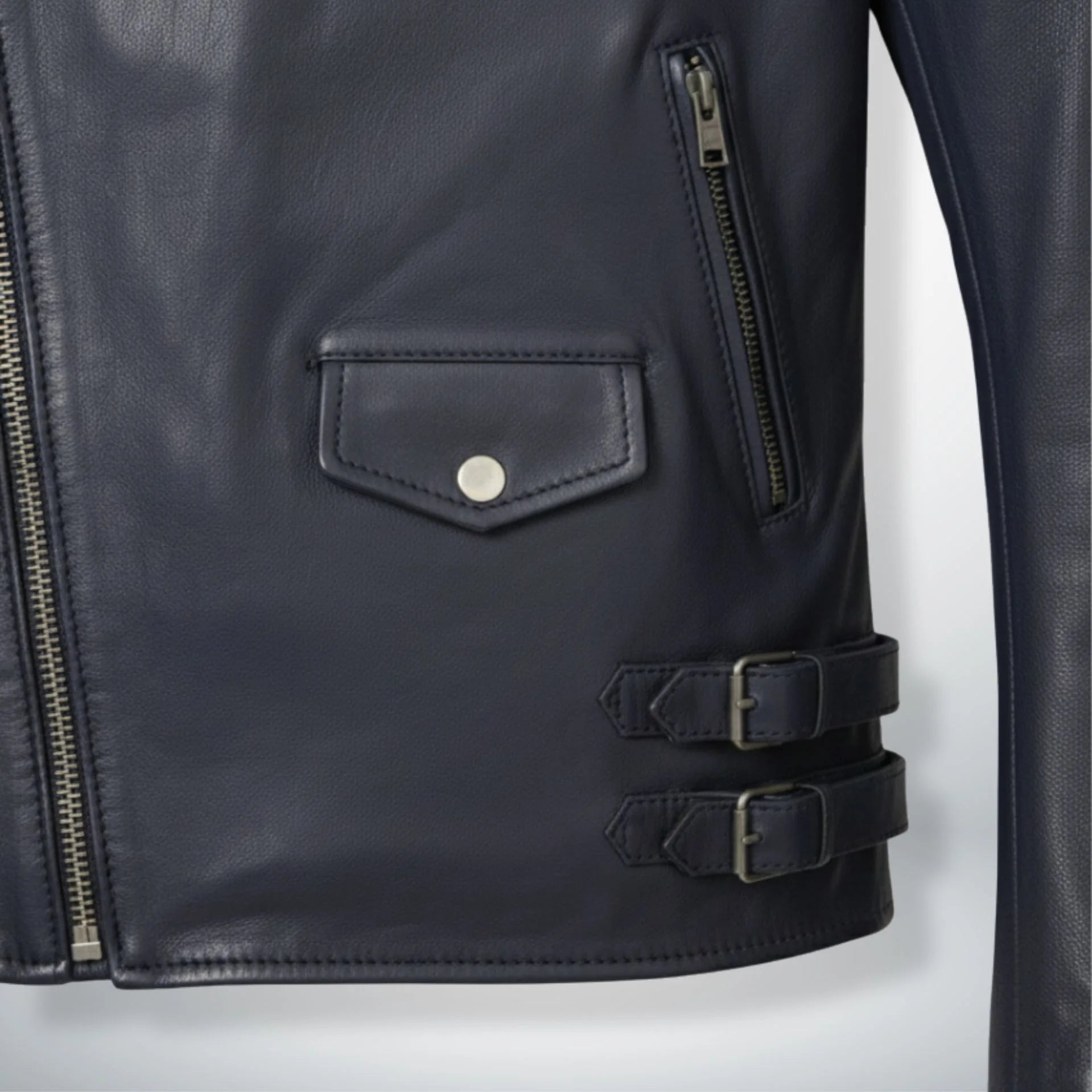 detail of pockets and side buckles on men's navy leather moto jacket.