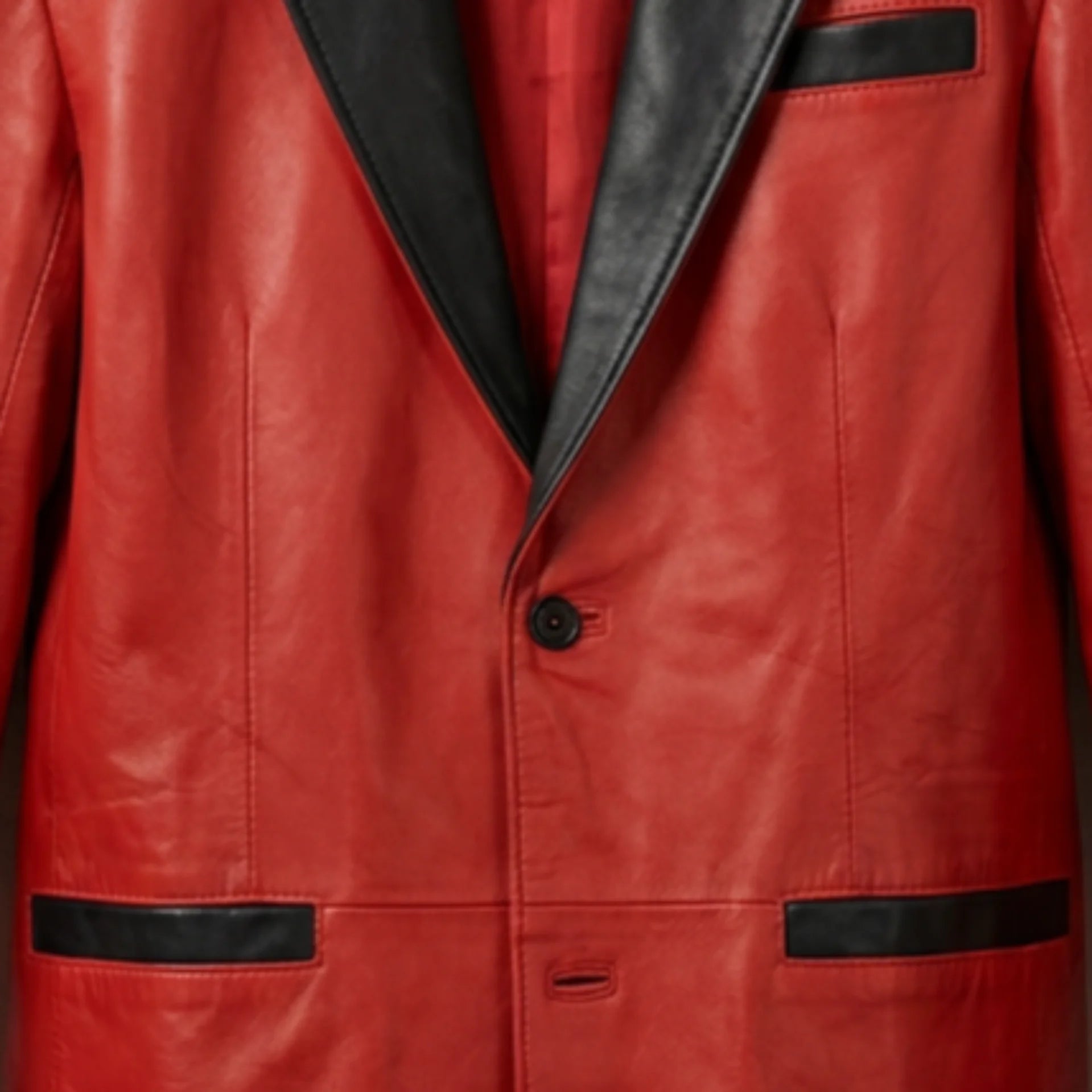 Front button and black pocket trim close up on men’s red leather blazer