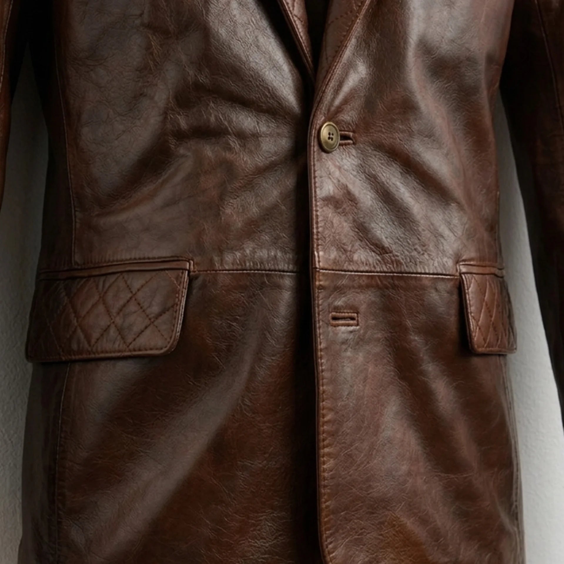 Front button and quilted pocket flap close up on men’s brown leather blazer jacket