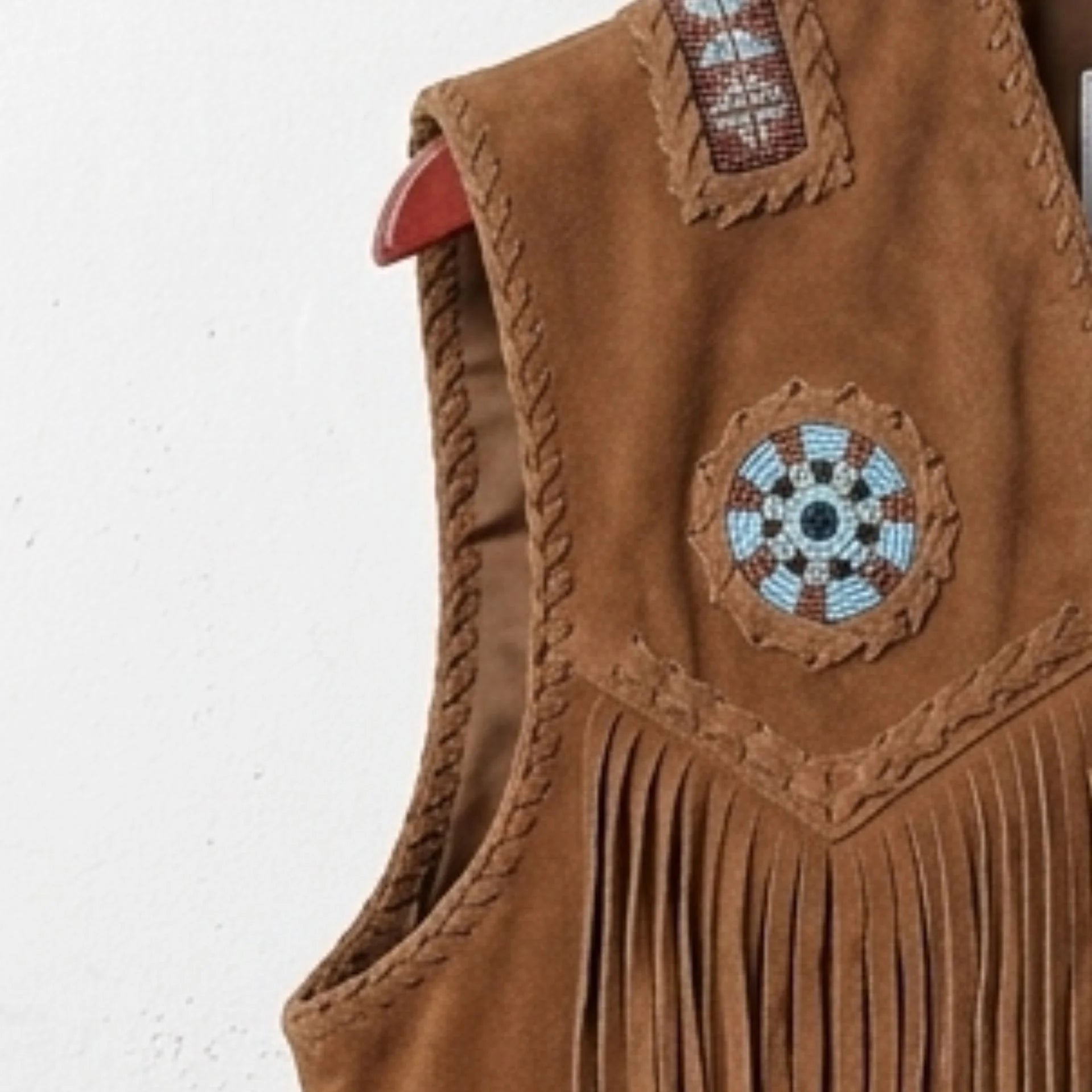 Close-up of fringe, bone-style accents and snap buttons on men's suede fringe western vest.