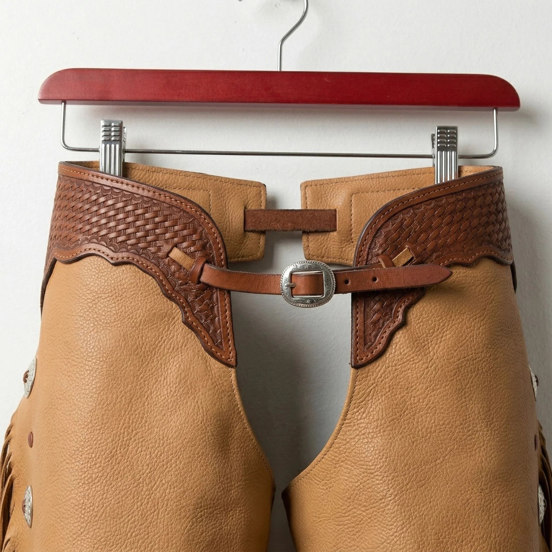 Close-up of tooled brown yoke and adjustable buckle on tan leather western chaps