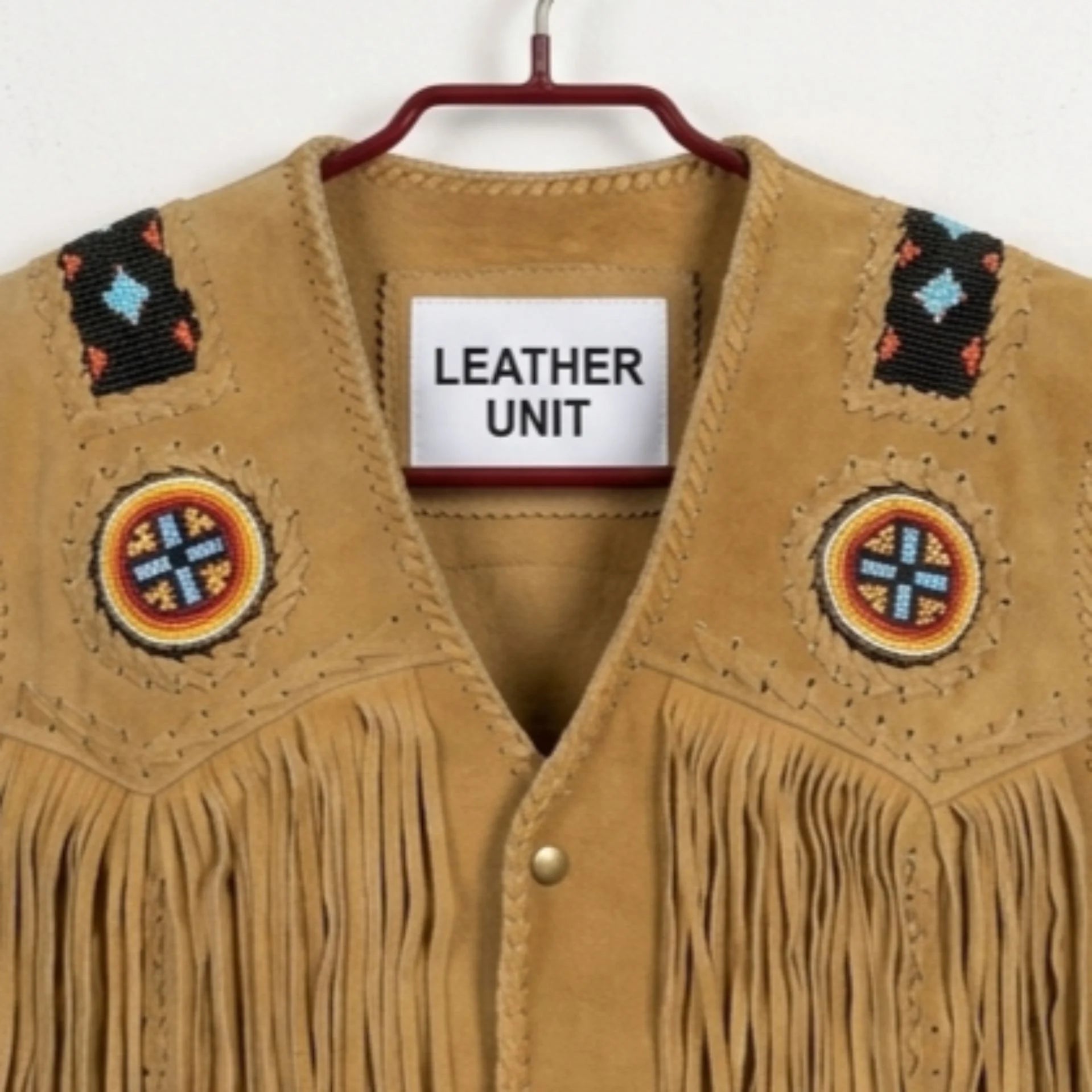 Close up of beaded shoulder patches and Leather Unit label on tan suede vest.