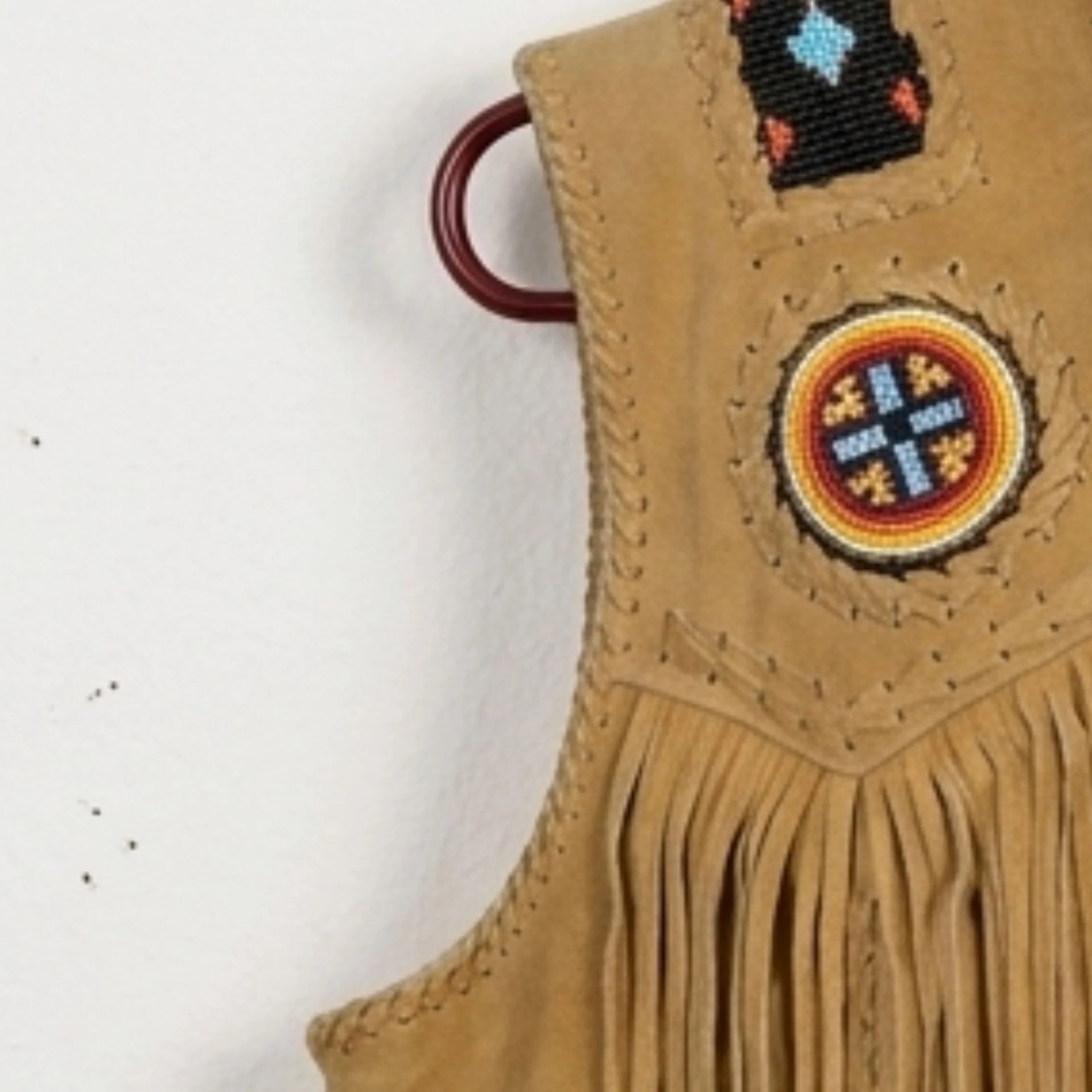 Detail of beadwork and chest fringe on men's tan western cowboy vest.