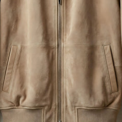 Close up of front zipper and slanted hand pockets on men's tan suede bomber jacket.