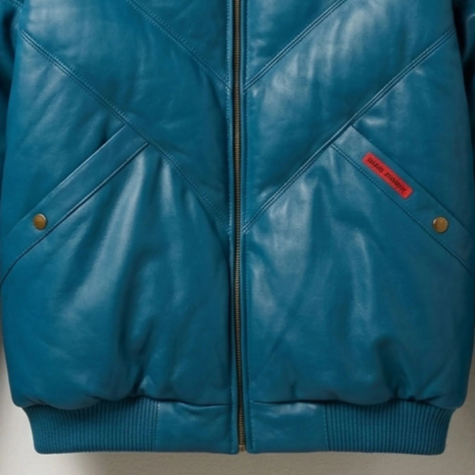 Detail of snap pockets on insulated teal leather jacket
