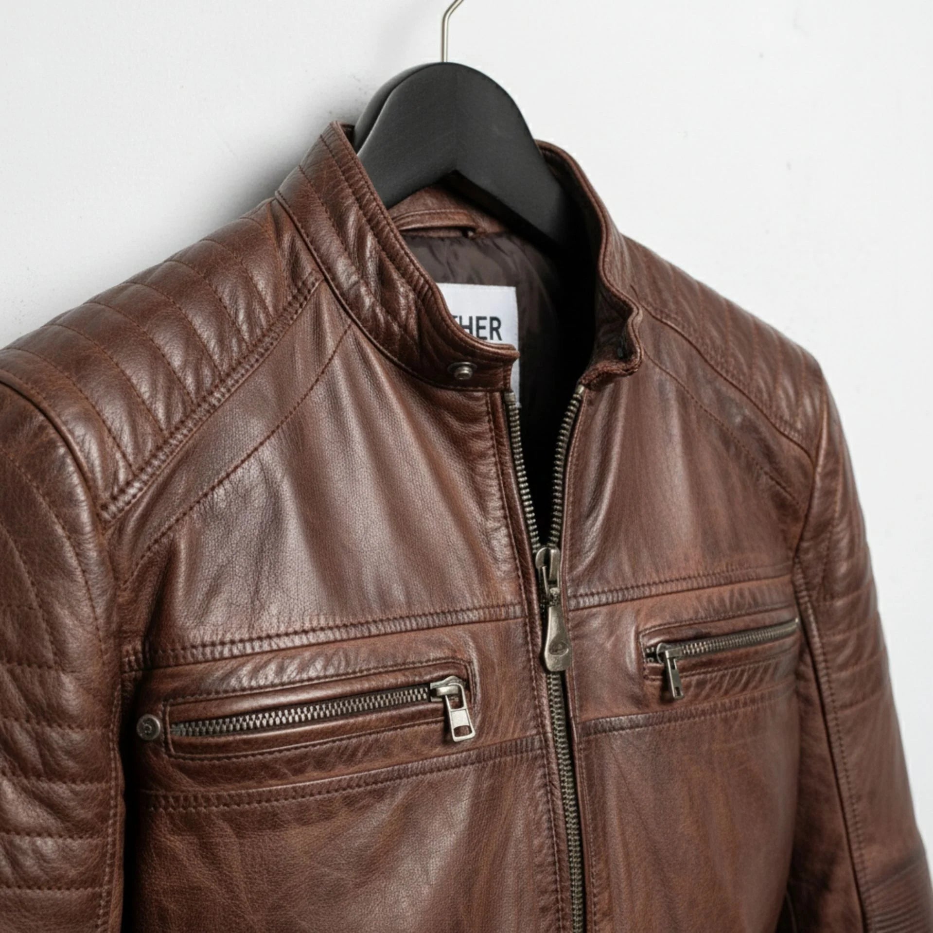 close up of collar and chest zipper pockets on men's brown leather cafe racer jacket.
