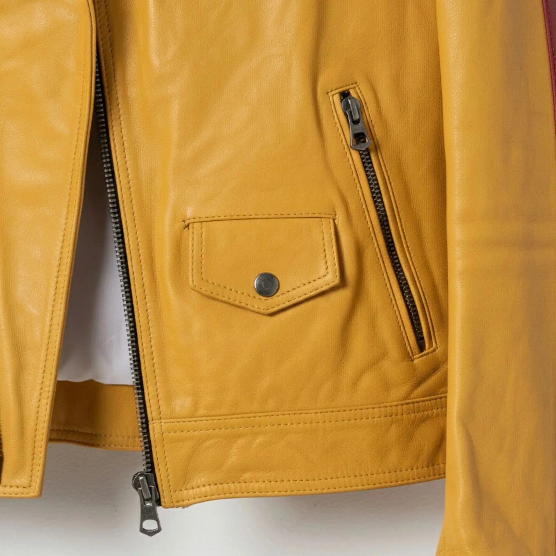 detail of pocket and zipper on men's yellow leather biker jacket.