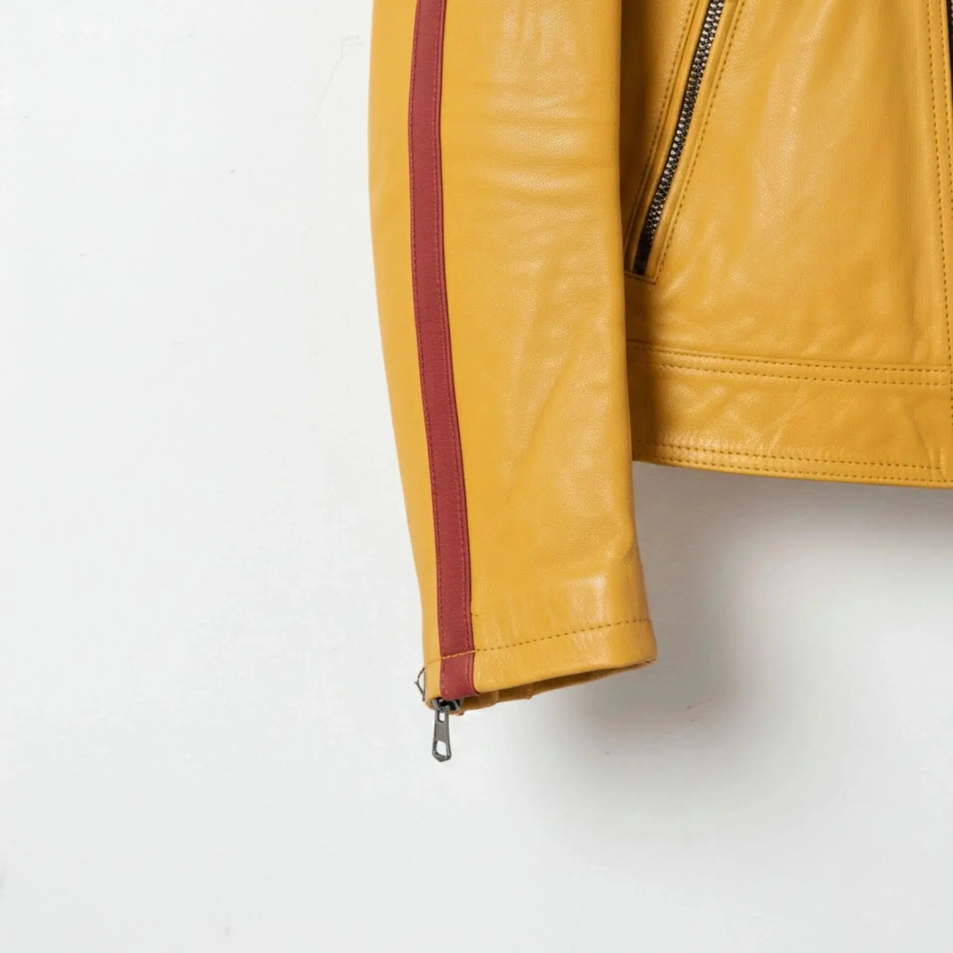 sleeve and cuff zipper close up on men's yellow leather jacket with red stripe.