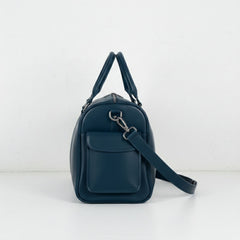 side view navy leather travel duffle with flap pocket and detachable strap.