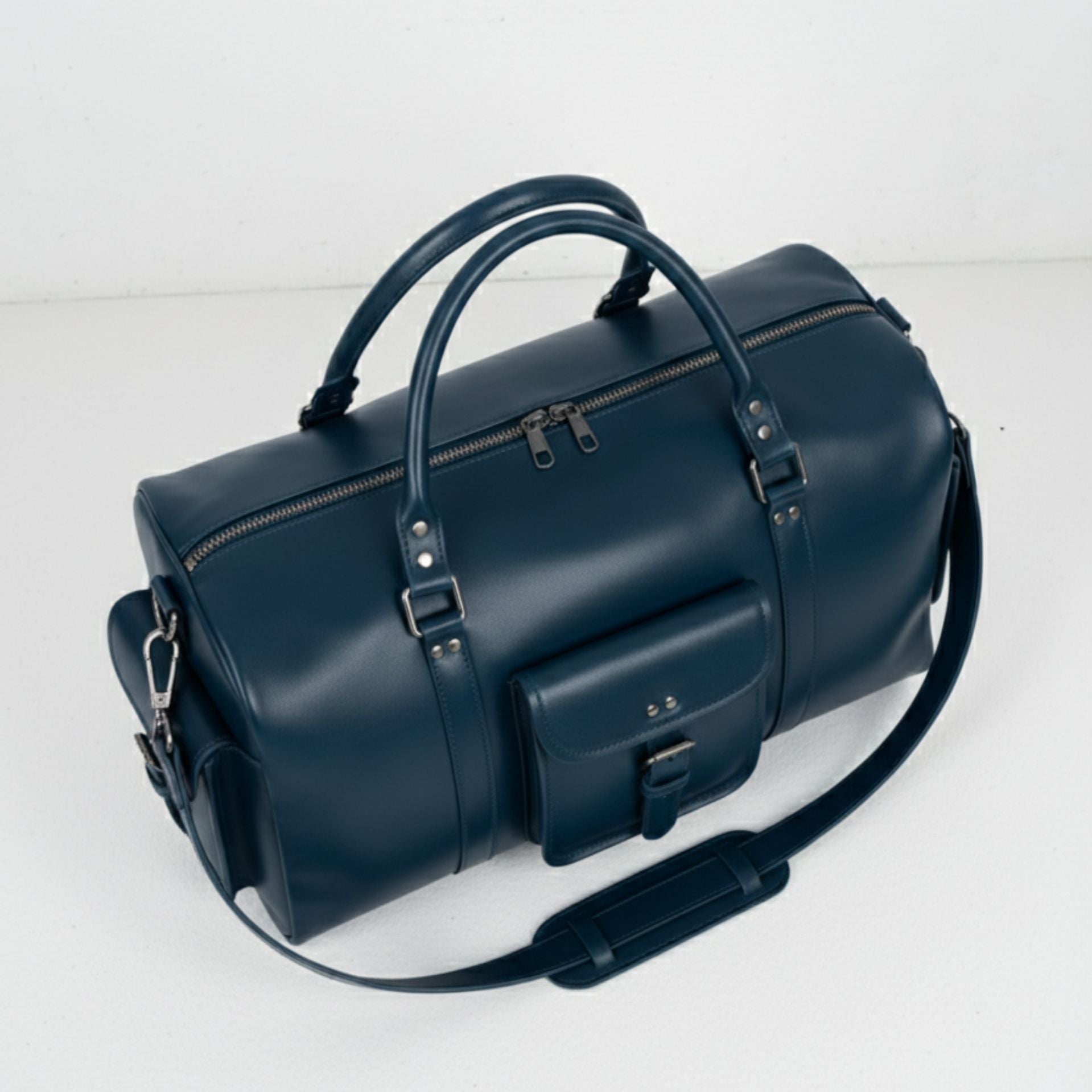 top angled view navy leather duffle bag showing double zip closure and handles.