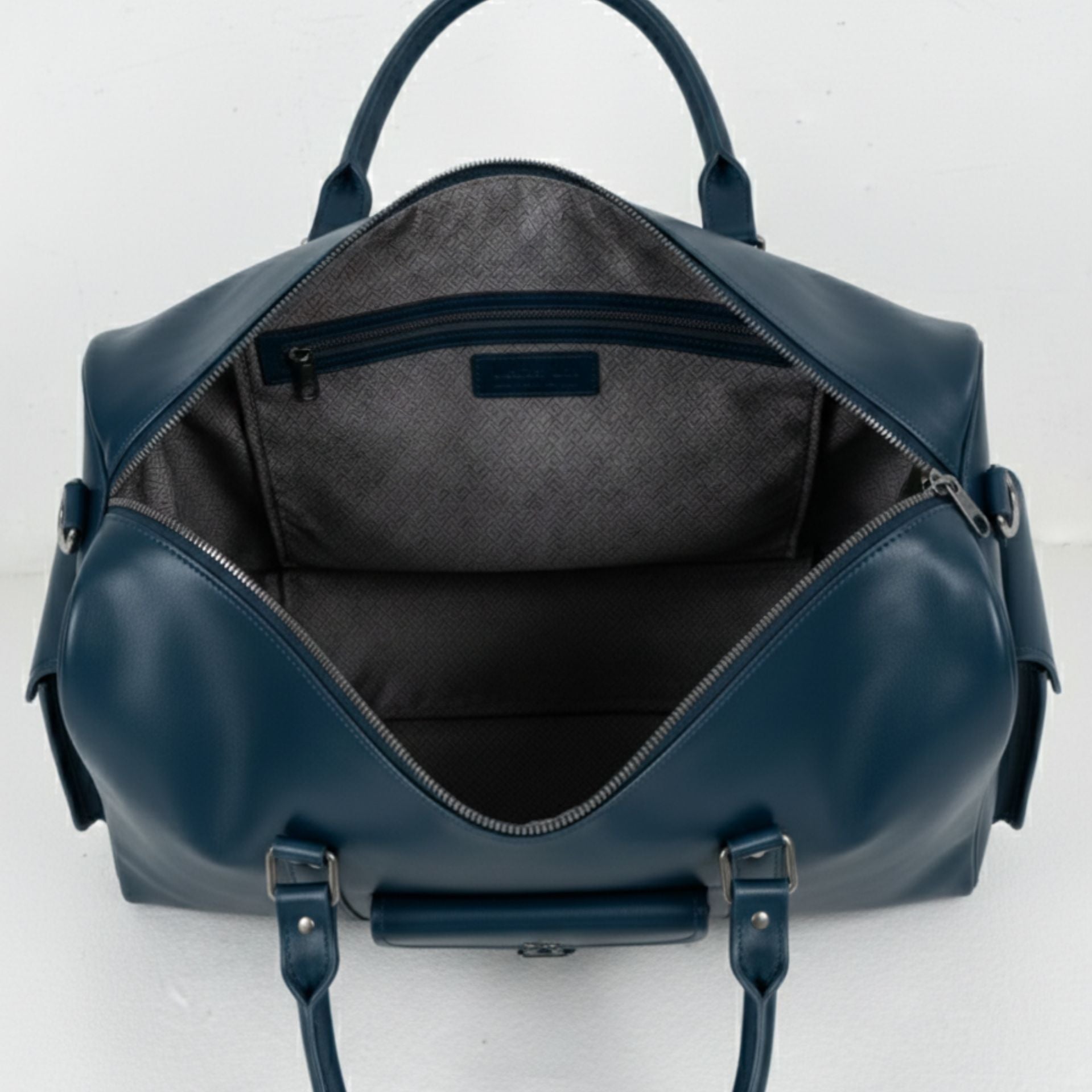 interior of navy leather duffle bag with grey lining and zip pocket.
